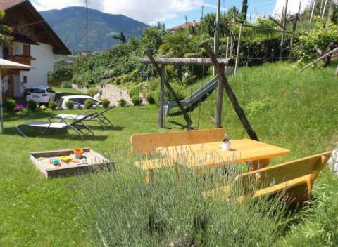Parco giochi con sabbiera, altalena e scivolo in giardino &ndash; Appartamenti vacanze per famiglie Langeshof Scena, Alto Adige