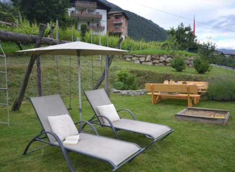 Sedie a sdraio con ombrellone e sabbiera nel giardino del Langeshof in Alto Adige