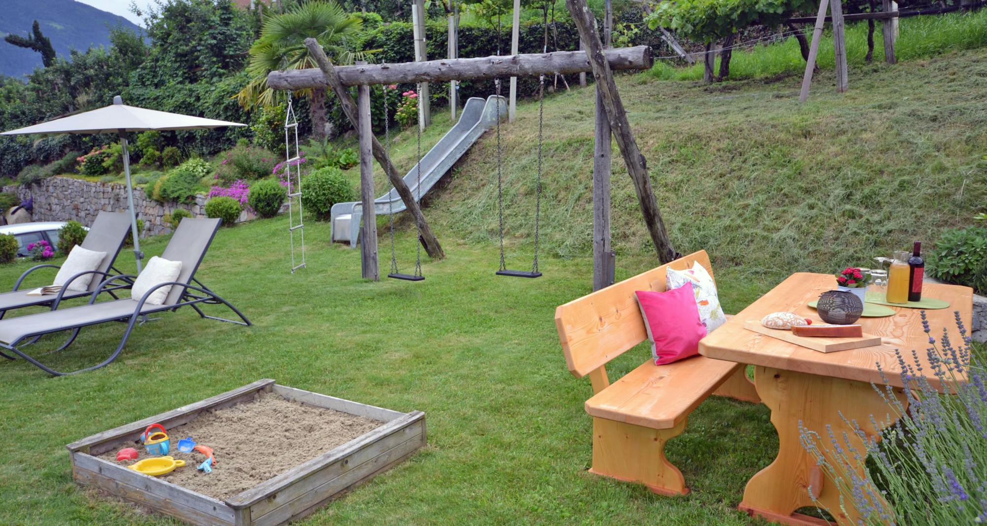 Kinderspielplatz mit Sandkasten, Schaukel und Rutsche im Garten &ndash; Familien-Ferienwohnungen Langeshof Schenna, Südtirol