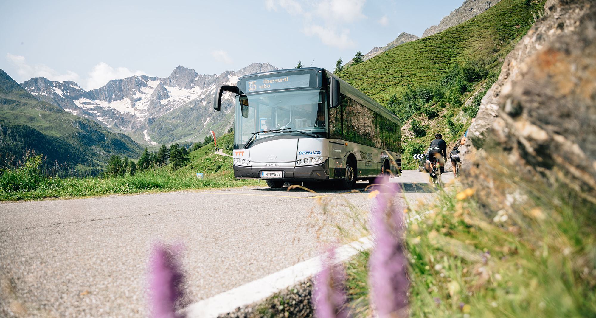Südtirol Bus auf der Timmelsjochstraße mit Radfahrern und Bergpanorama – Öffentlicher Nahverkehr nahe Schenna, Südtirol